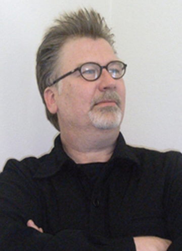 Photo of Scott Michaelsen. Older middle aged man with greyish brown hair and goatee, glasses, and black shirt.