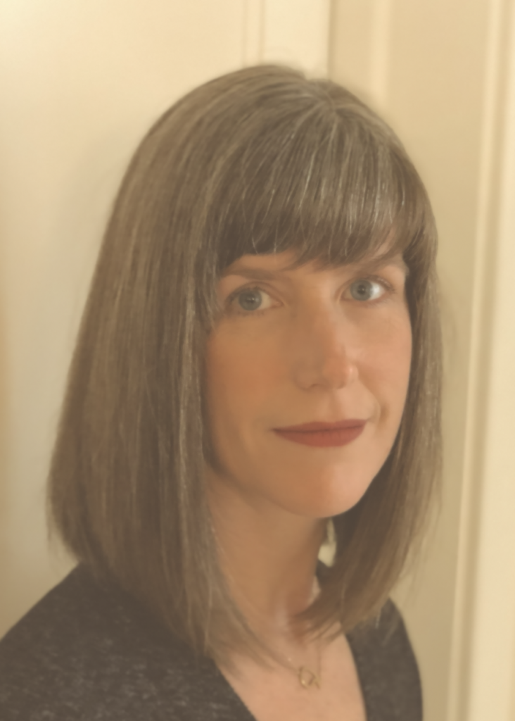 Woman with grey hair and blouse looking at camera smiling.