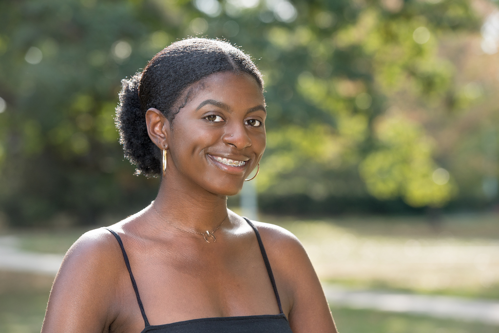 a girl with dark brown hair up in a bun wearing a black tank top