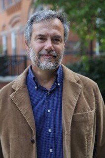 Photo of David Stowe. Portrait of older man with grey hair and beard, wearing blue shirt with black suit coat.