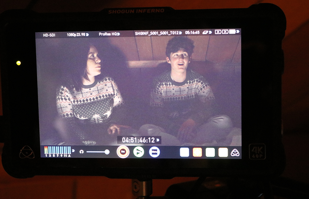 a man and a woman in matching sweaters sitting next to each other on a couch