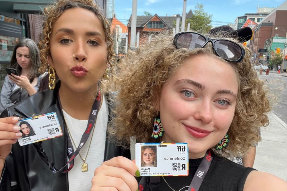 Two young women showing their ID cards on lanyards. 