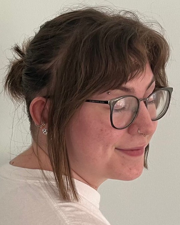A picture of a person with brown hair and glasses wearing a white shirt