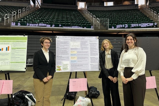 Three women standing next to a research poster.