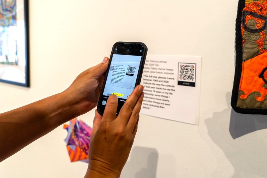 A picture of two hands holding a phone up to a QR code. 