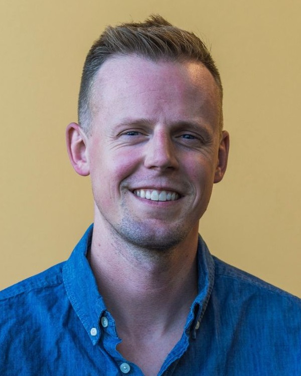 A picture of a man with short blond hair and a blue shirt 